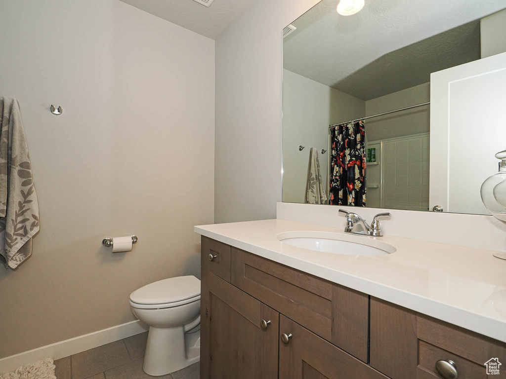 Full bath featuring vanity, toilet, tile patterned flooring, baseboards, and a shower with shower curtain