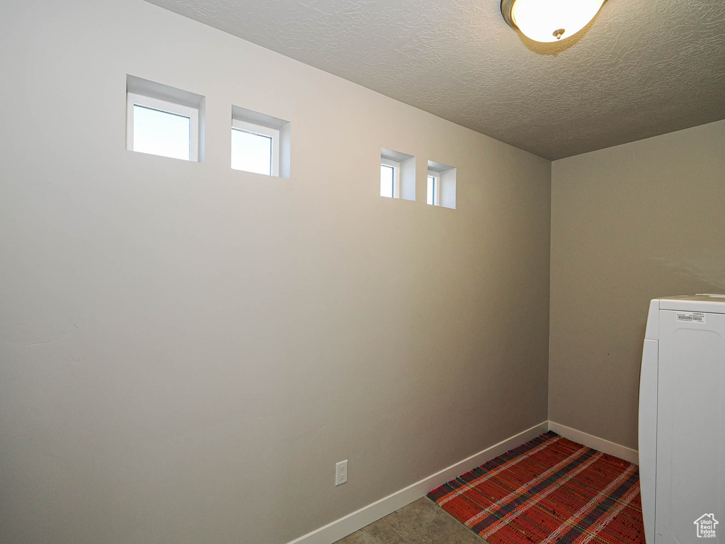 Washroom with washer / clothes dryer, baseboards, and a textured ceiling