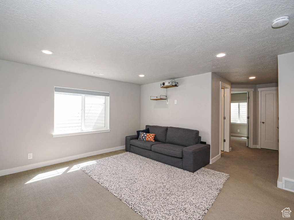 Living room featuring light colored carpet, baseboards, recessed lighting, and a textured ceiling