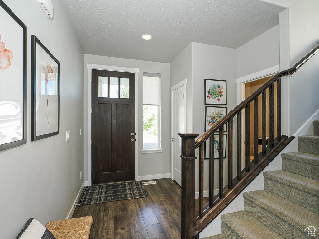 Entryway featuring dark wood-type flooring, stairs, baseboards, a textured ceiling, and recessed lighting