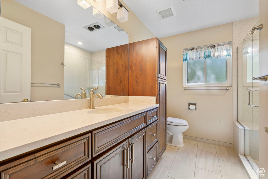 Full bathroom with vanity, a shower stall, baseboards, and toilet