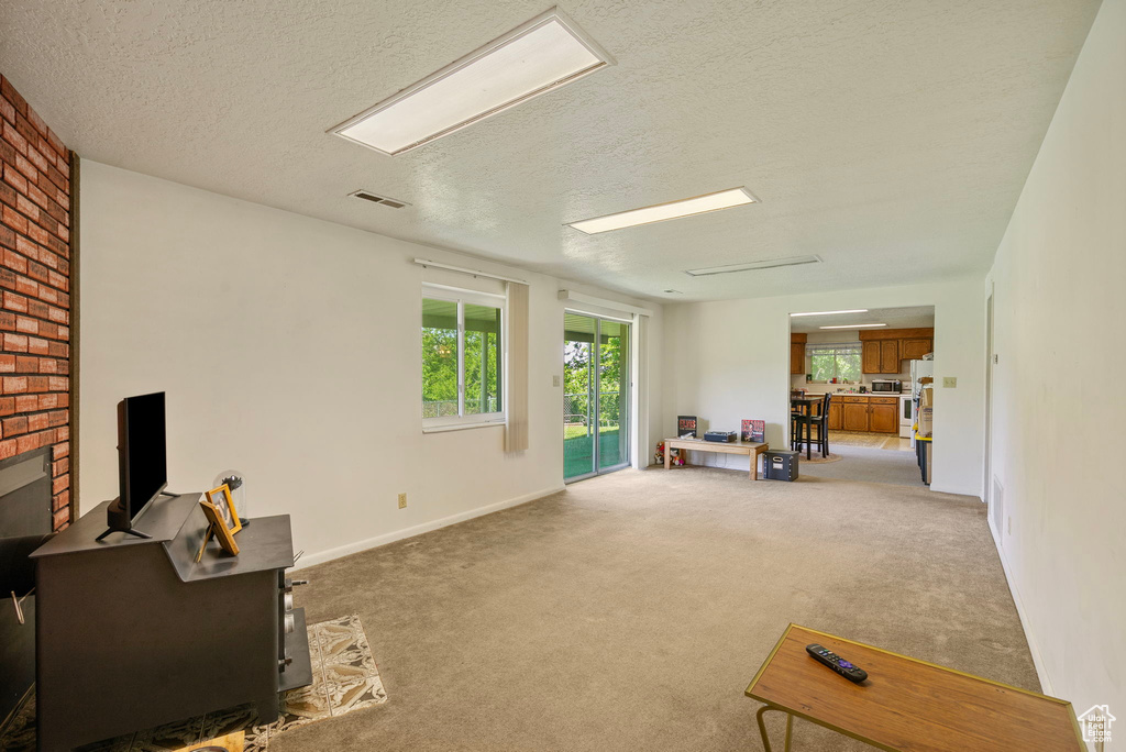 Living area with a textured ceiling, light colored carpet, and baseboards