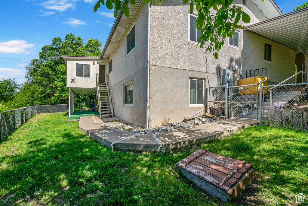 Back of property featuring a gate, stairway, and stucco siding