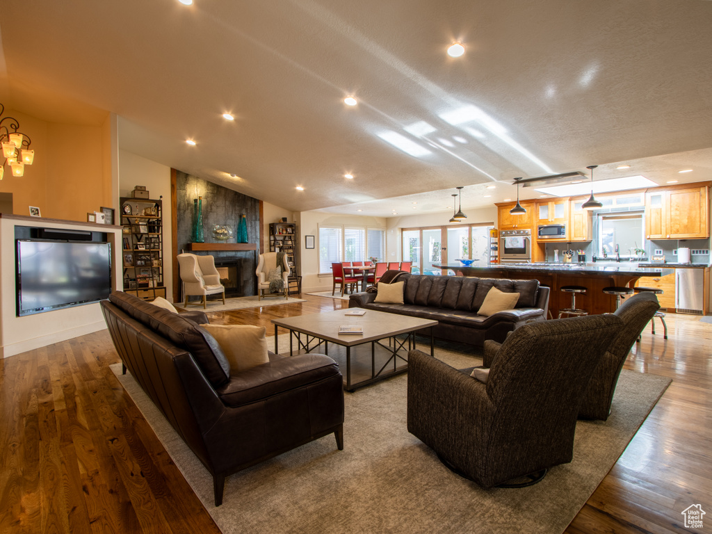 Living room featuring recessed lighting, a large fireplace, wood finished floors, vaulted ceiling, and baseboards