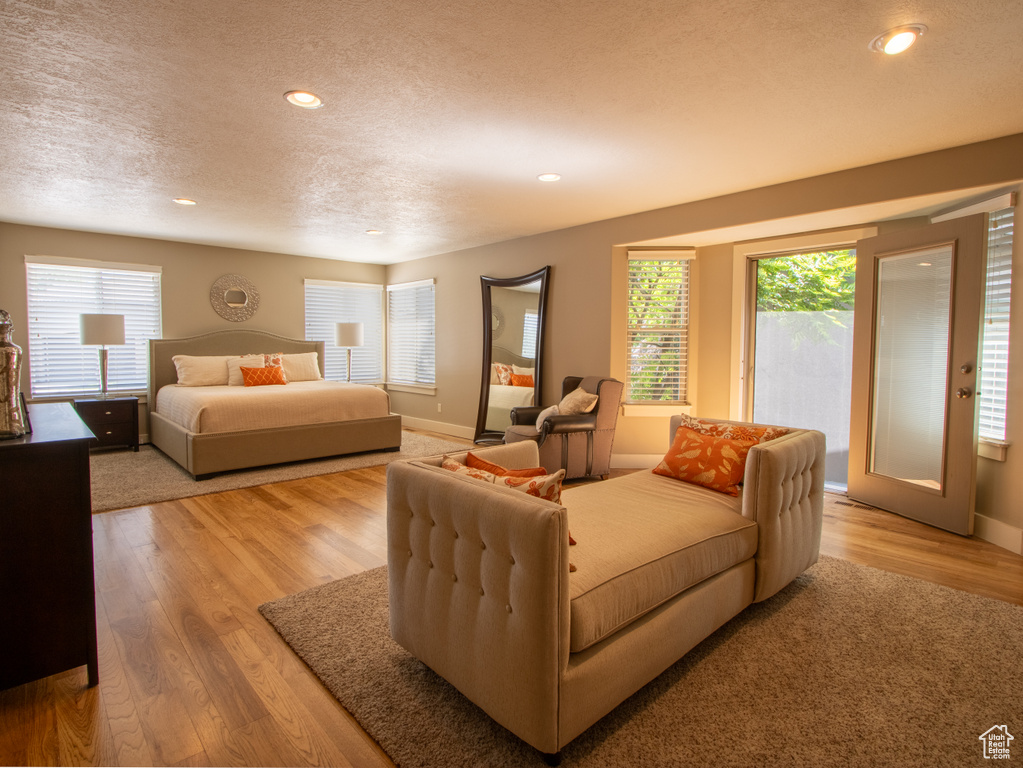Bedroom with a textured ceiling, multiple windows, light wood-style floors, recessed lighting, and baseboards