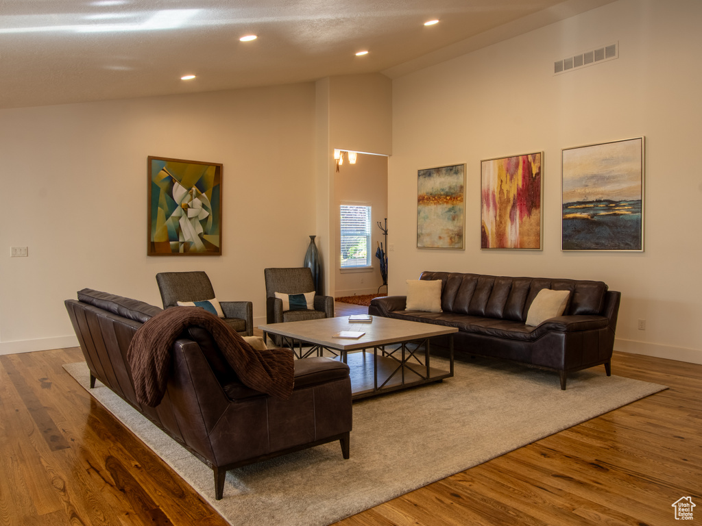 Living room featuring baseboards, wood finished floors, recessed lighting, and high vaulted ceiling