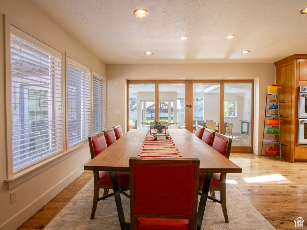 Dining area featuring french doors, recessed lighting, light wood-type flooring, a textured ceiling, and baseboards