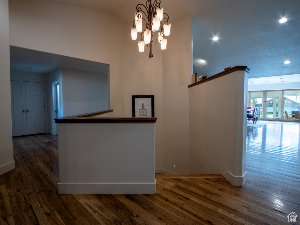 Hall with baseboards, a chandelier, wood finished floors, recessed lighting, and high vaulted ceiling