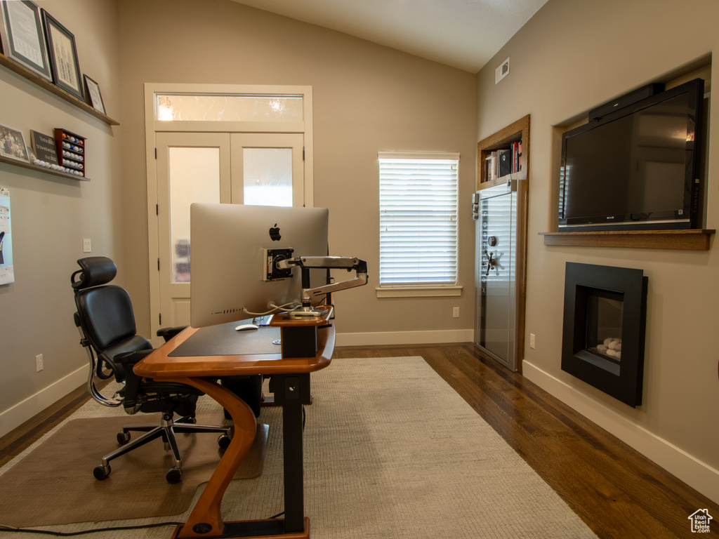 Office space with dark wood-style flooring, baseboards, and lofted ceiling