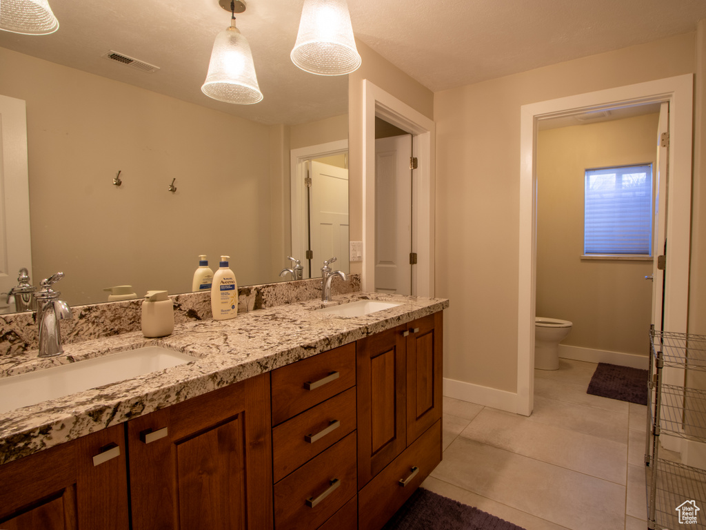 Full bathroom featuring double vanity, toilet, baseboards, and tile patterned flooring