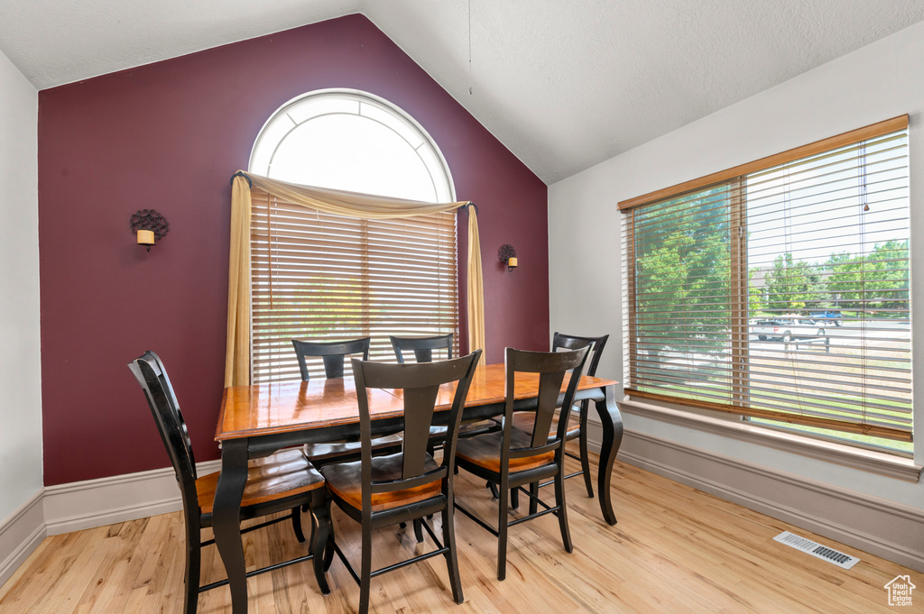 Dining area with lofted ceiling, light wood-type flooring, and baseboards
