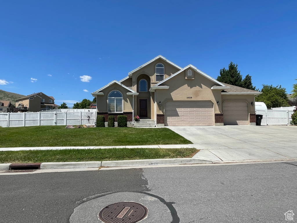 View of front facade with an attached garage, driveway, stucco siding, and brick siding