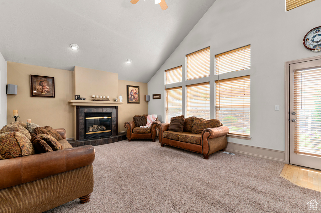 Living area with carpet flooring, healthy amount of natural light, a fireplace, and high vaulted ceiling