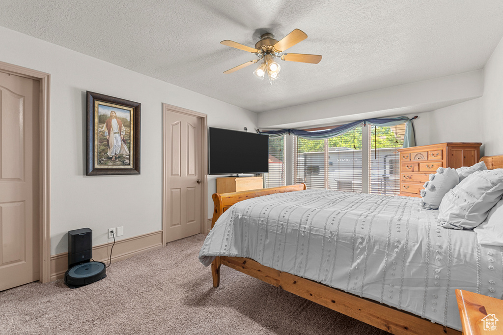Bedroom featuring carpet floors, a textured ceiling, a ceiling fan, and baseboards
