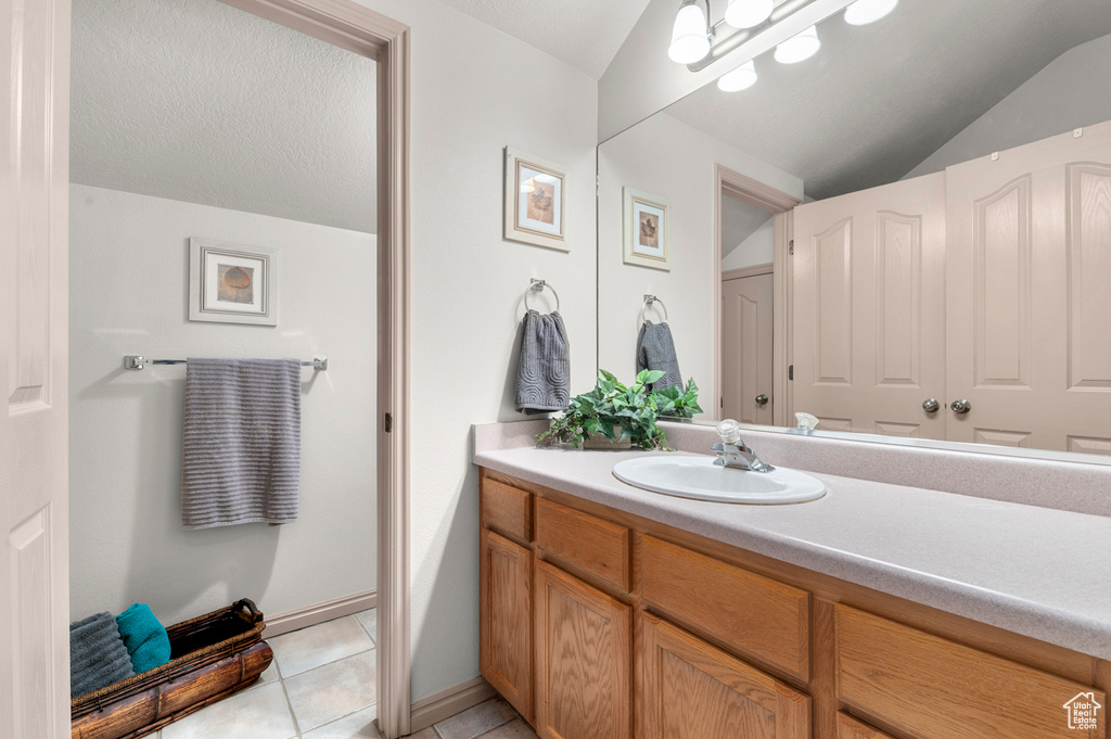 Bathroom featuring vaulted ceiling, vanity, and tile patterned floors