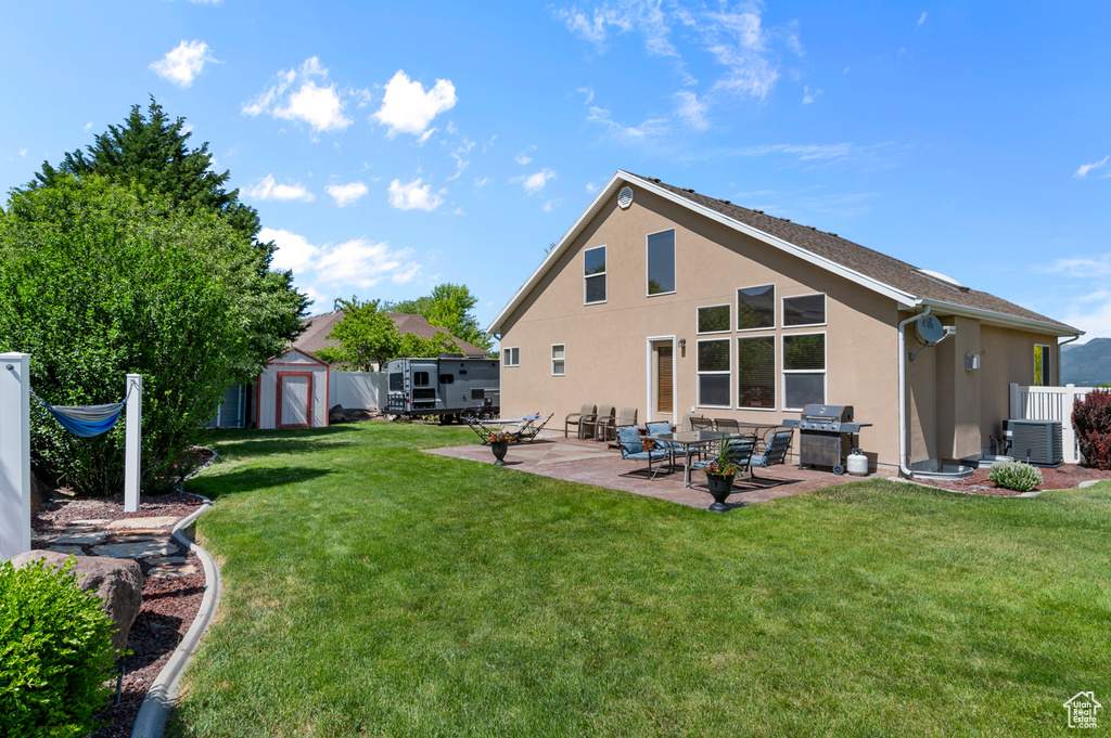 Back of property with stucco siding, a patio, central AC, and a lawn