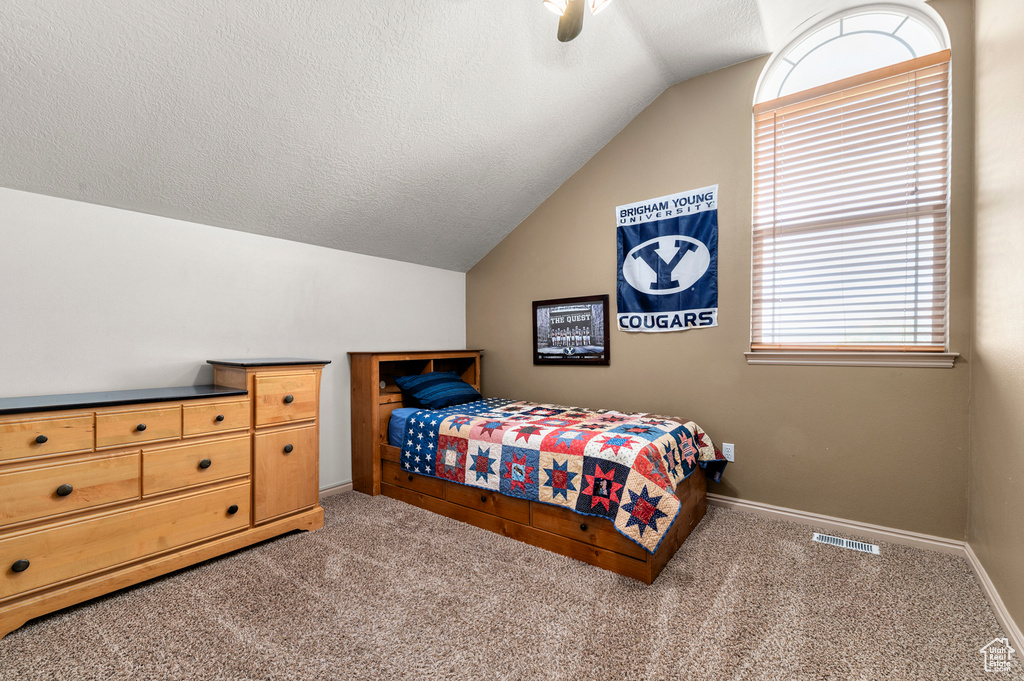 Carpeted bedroom featuring lofted ceiling, baseboards, a textured ceiling, and ceiling fan