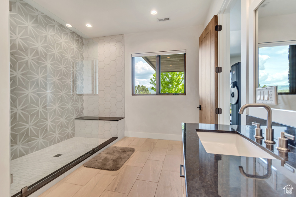 Bathroom with a sink, plenty of natural light, recessed lighting, and a tile shower