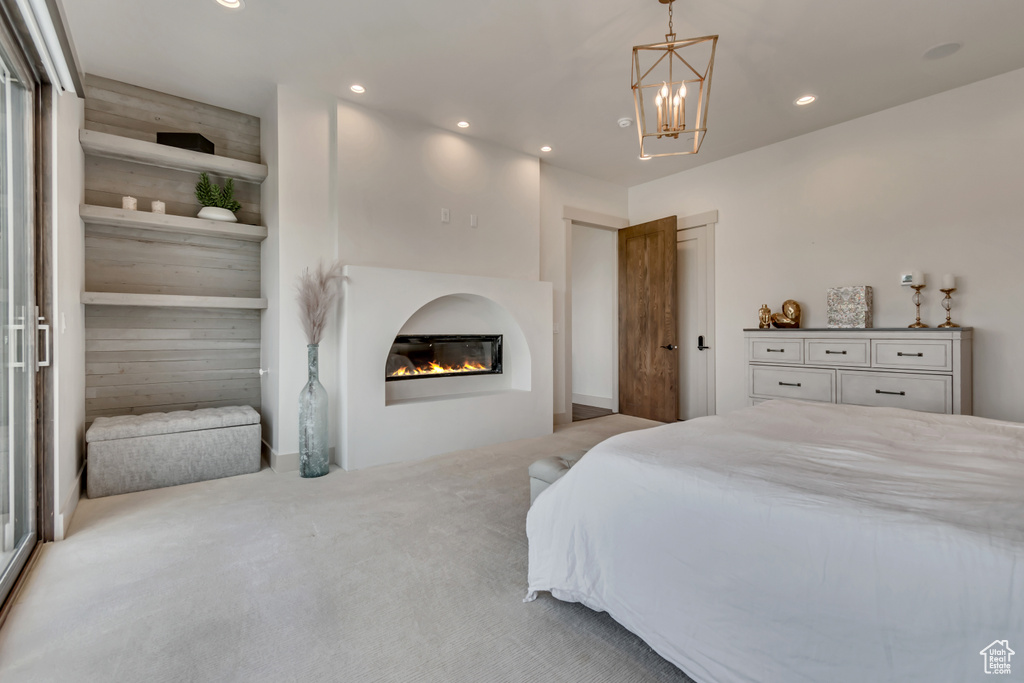 Carpeted bedroom with recessed lighting, a glass covered fireplace, and a chandelier