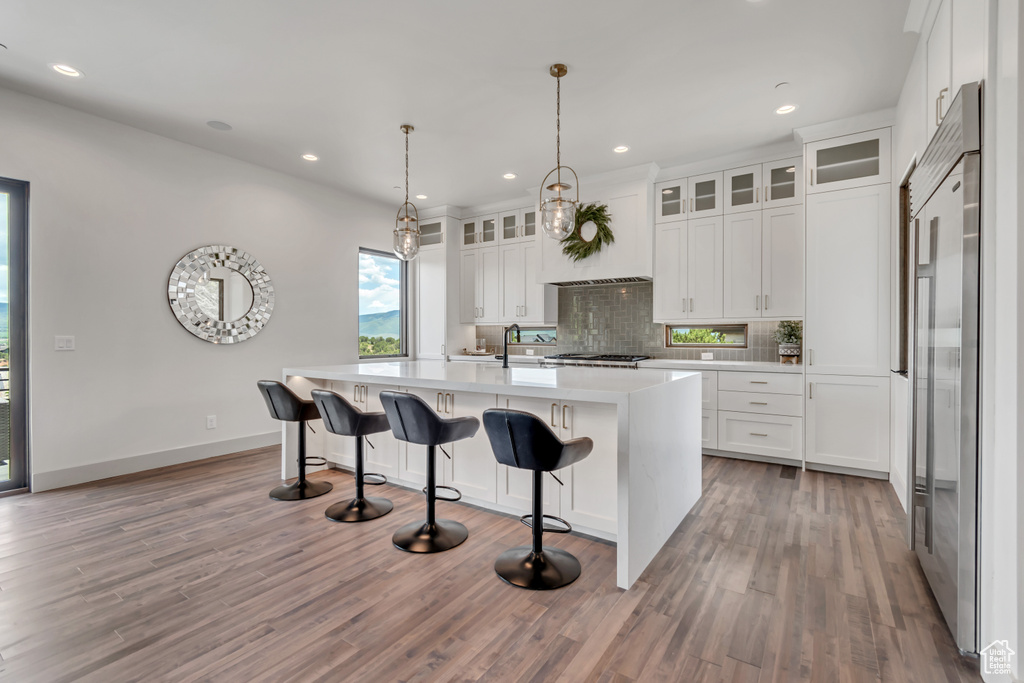 Kitchen with decorative backsplash, light countertops, light wood-style floors, white cabinets, and recessed lighting