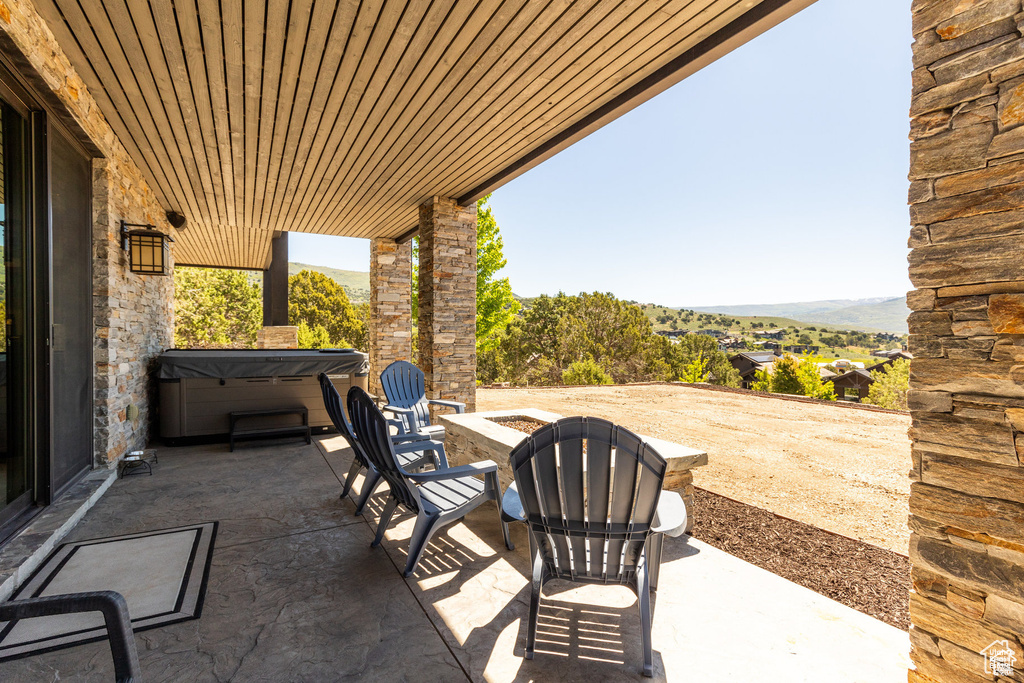 View of patio / terrace featuring a hot tub, an outdoor fire pit, and a mountain view