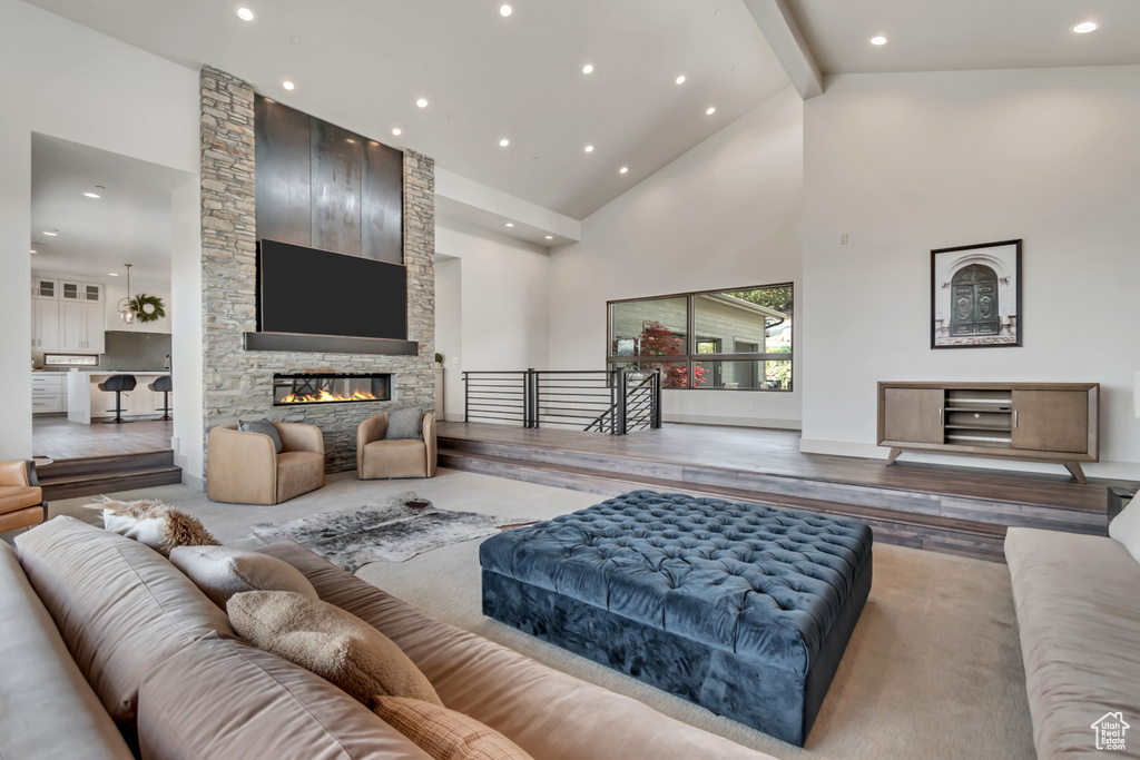 Living area featuring high vaulted ceiling, beam ceiling, recessed lighting, a fireplace, and wood finished floors