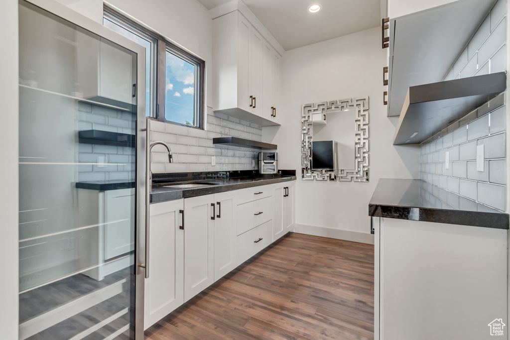 Kitchen featuring a sink, dark countertops, dark wood-style floors, baseboards, and recessed lighting