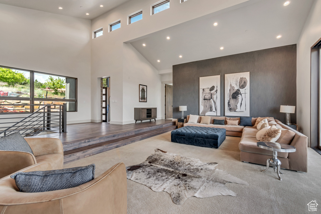 Carpeted living room with recessed lighting, a towering ceiling, and baseboards