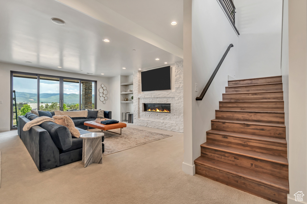 Carpeted living area with a fireplace, stairway, recessed lighting, and built in features