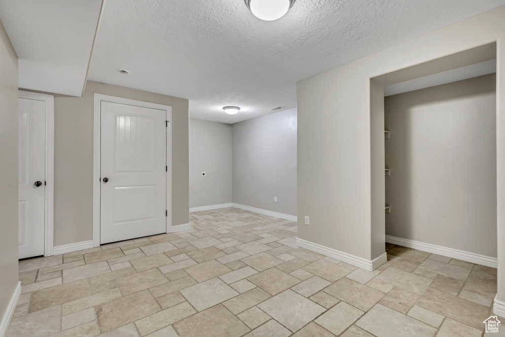 Unfurnished room featuring a textured ceiling, baseboards, and light stone finish floors
