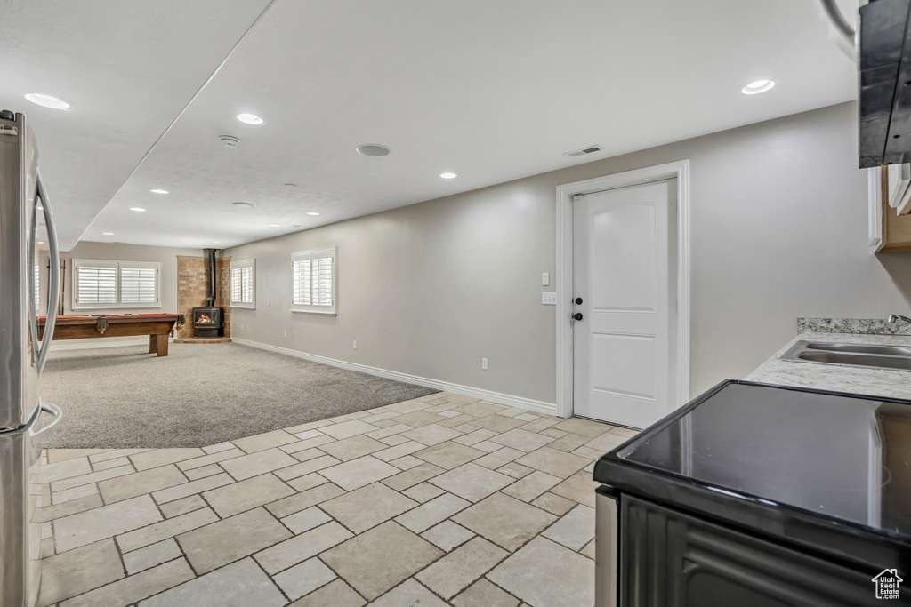 Kitchen with black / electric stove, a sink, freestanding refrigerator, recessed lighting, and light carpet