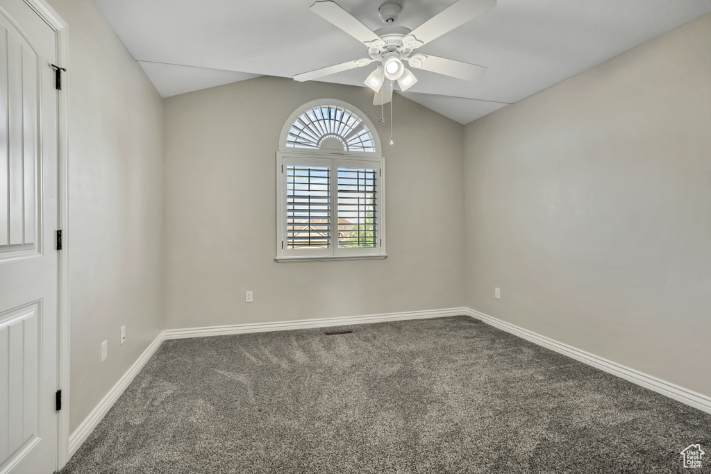 Spare room featuring carpet floors, ceiling fan, baseboards, and lofted ceiling
