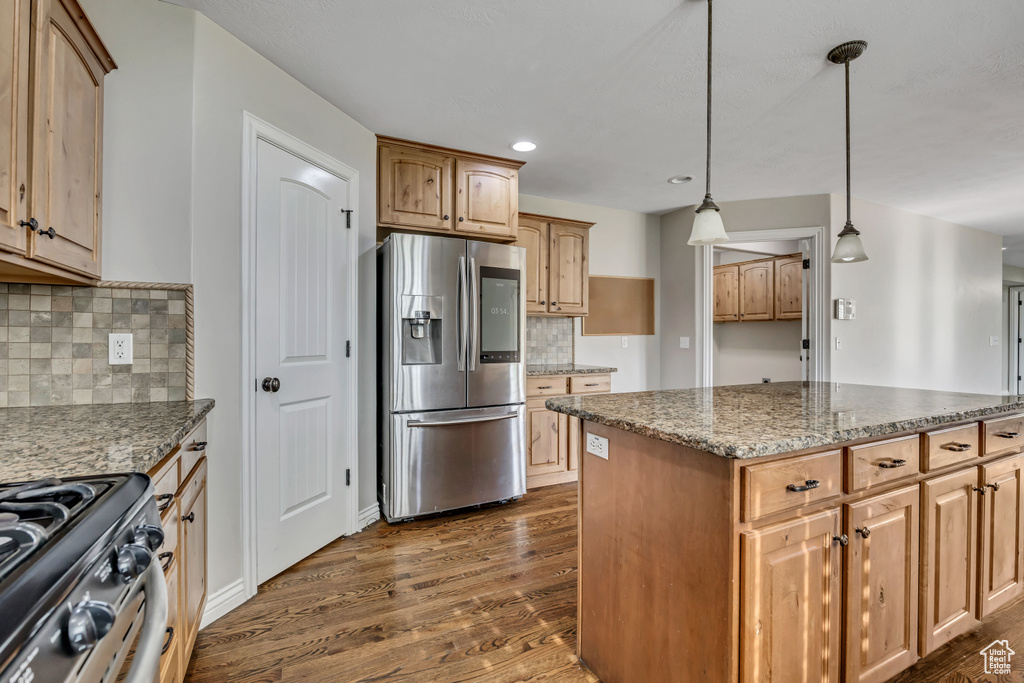 Kitchen with appliances with stainless steel finishes, dark wood-style flooring, stone countertops, decorative backsplash, and recessed lighting