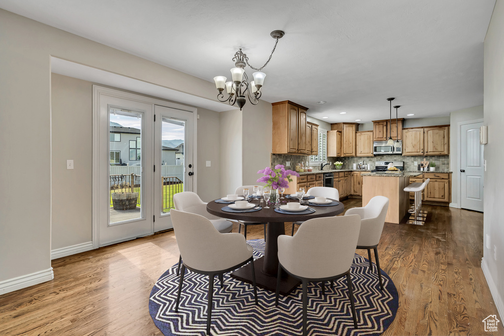 Dining room with wood finished floors, a chandelier, baseboards, and recessed lighting