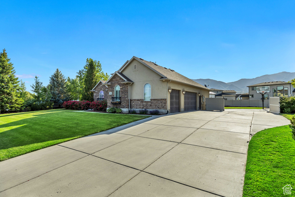 View of front of property with an attached garage, concrete driveway, stucco siding, a mountain view, and brick siding