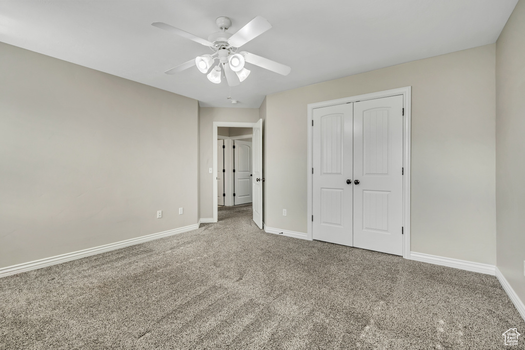 Unfurnished bedroom with carpet flooring, baseboards, a closet, and a ceiling fan