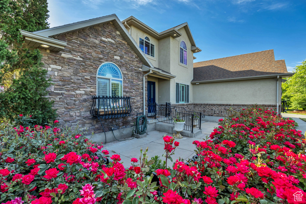 Traditional home with stucco siding, stone siding, and a patio area