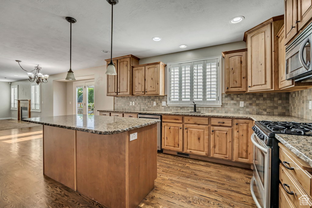 Kitchen with appliances with stainless steel finishes, a sink, backsplash, wood finished floors, and recessed lighting