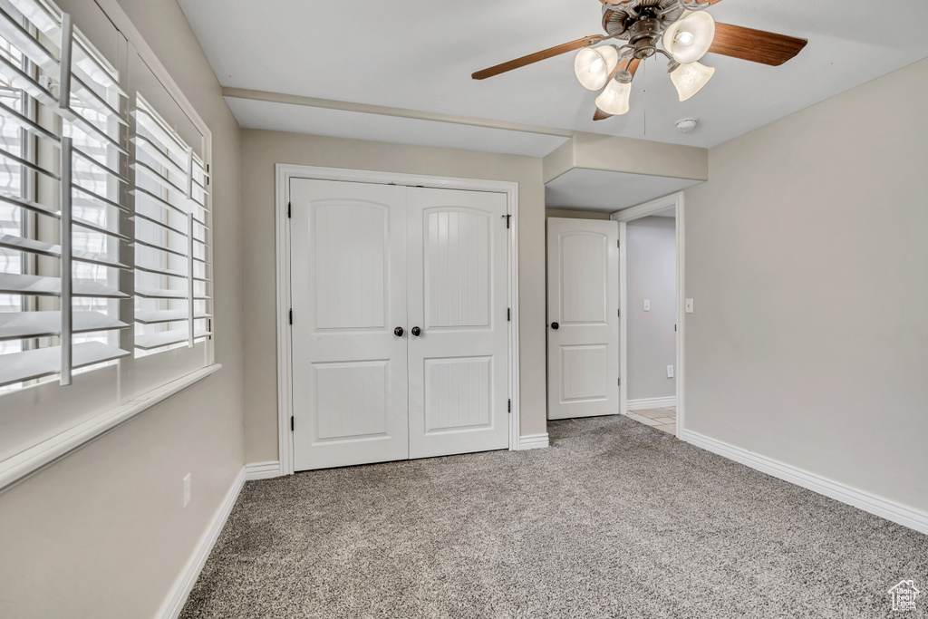 Unfurnished bedroom featuring carpet, baseboards, a closet, and a ceiling fan