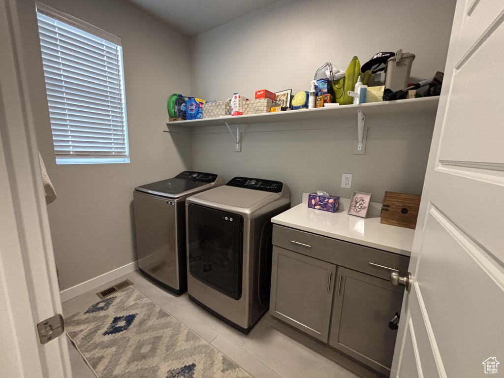 Laundry room with washer and clothes dryer, light tile patterned flooring, and cabinet space