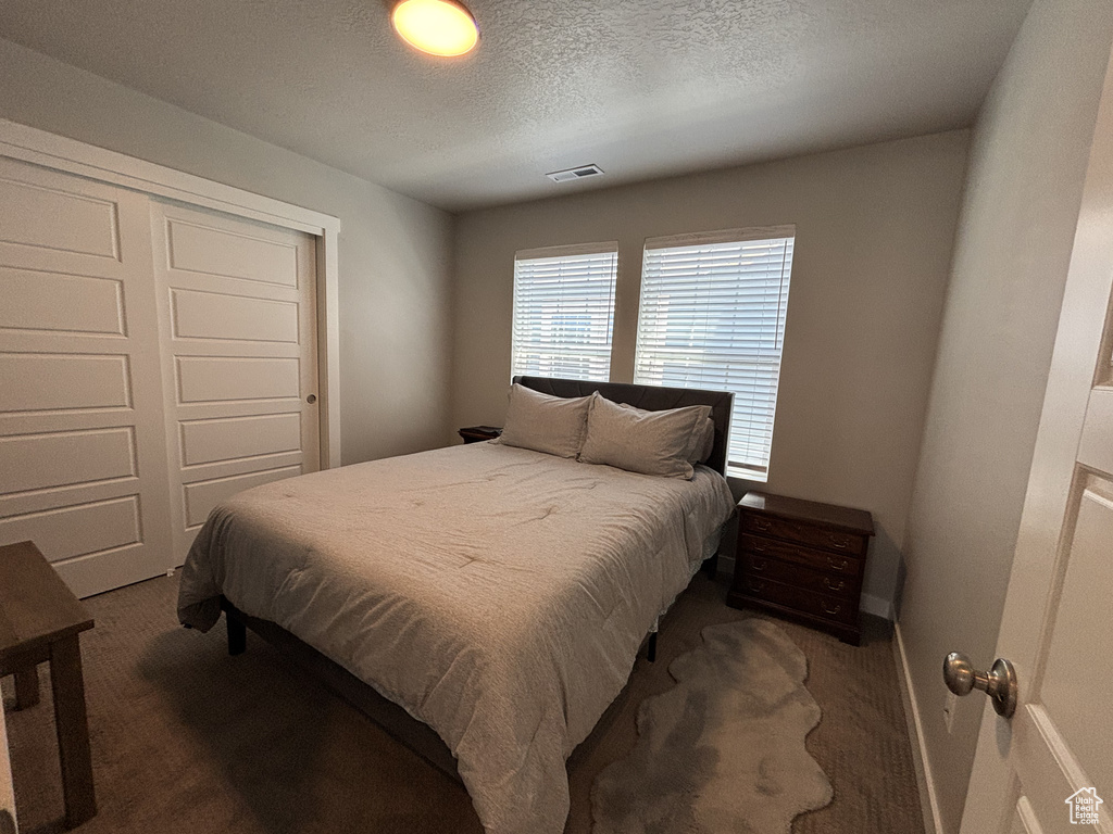 Bedroom featuring carpet, a closet, a textured ceiling, and baseboards