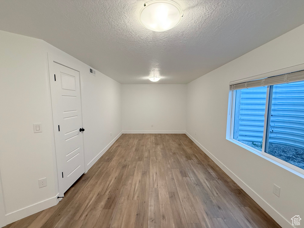 Spare room with a textured ceiling, wood finished floors, and baseboards