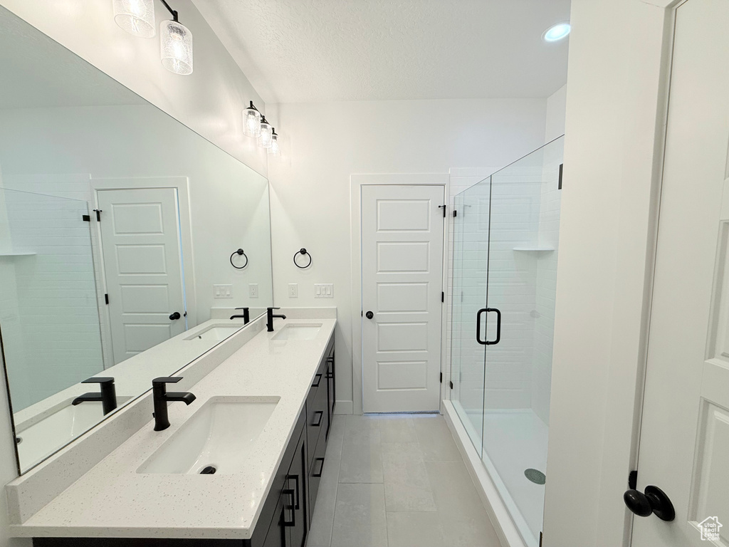 Full bath featuring double vanity, a shower stall, and tile patterned floors