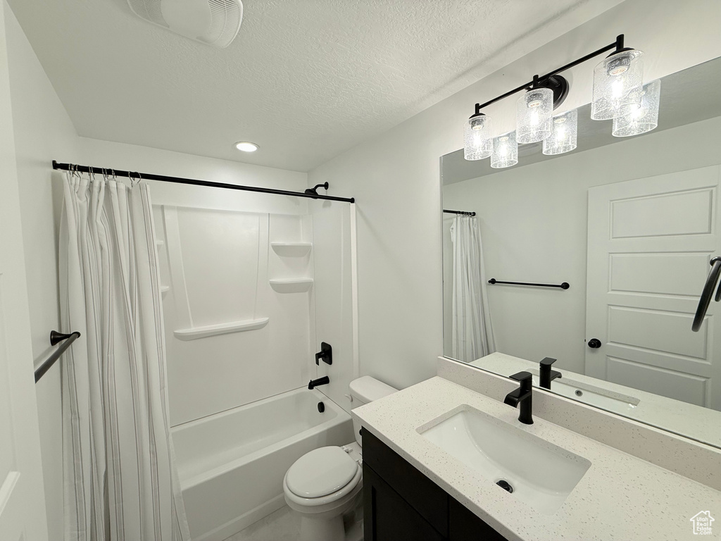 Full bathroom with vanity, toilet, shower / bath combo with shower curtain, a textured ceiling, and recessed lighting