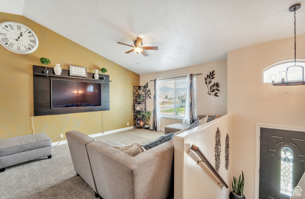 Carpeted living area featuring lofted ceiling, ceiling fan, and baseboards