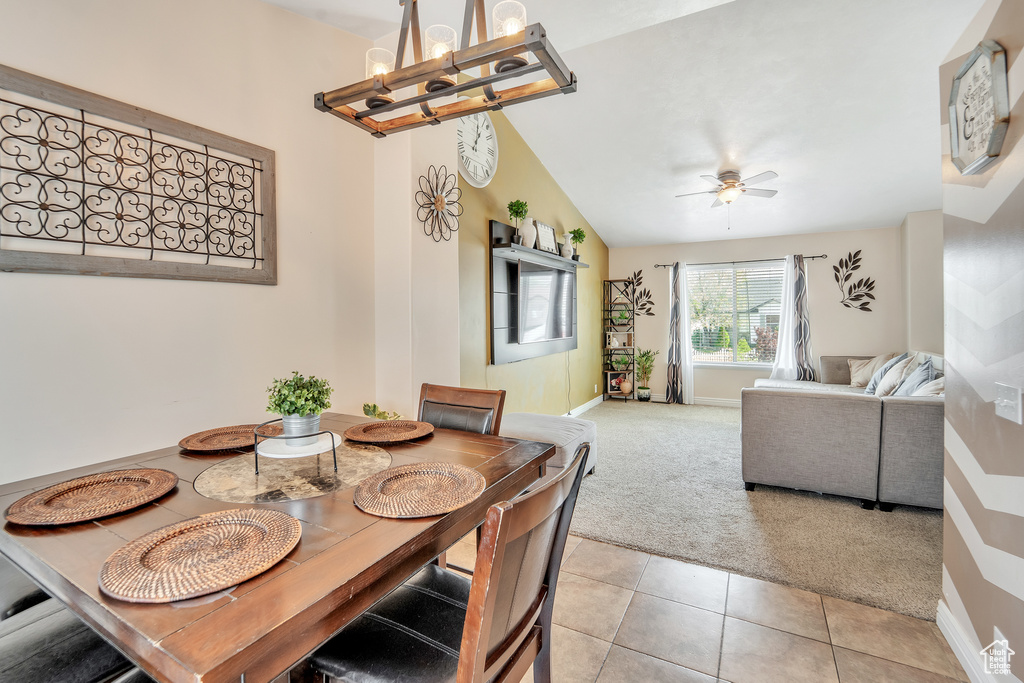 Dining space featuring light colored carpet, a chandelier, a ceiling fan, baseboards, and light tile patterned flooring