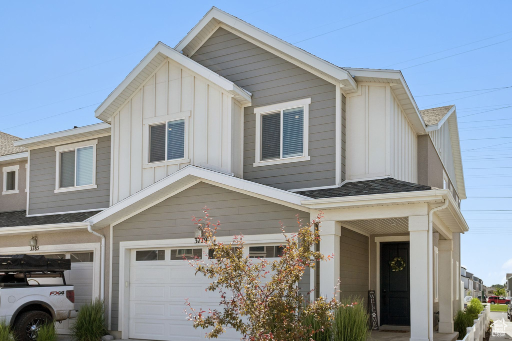 Multi unit property featuring board and batten siding, an attached garage, and roof with shingles