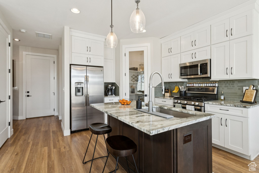 Kitchen featuring stainless steel appliances, backsplash, light wood-style floors, white cabinets, and recessed lighting