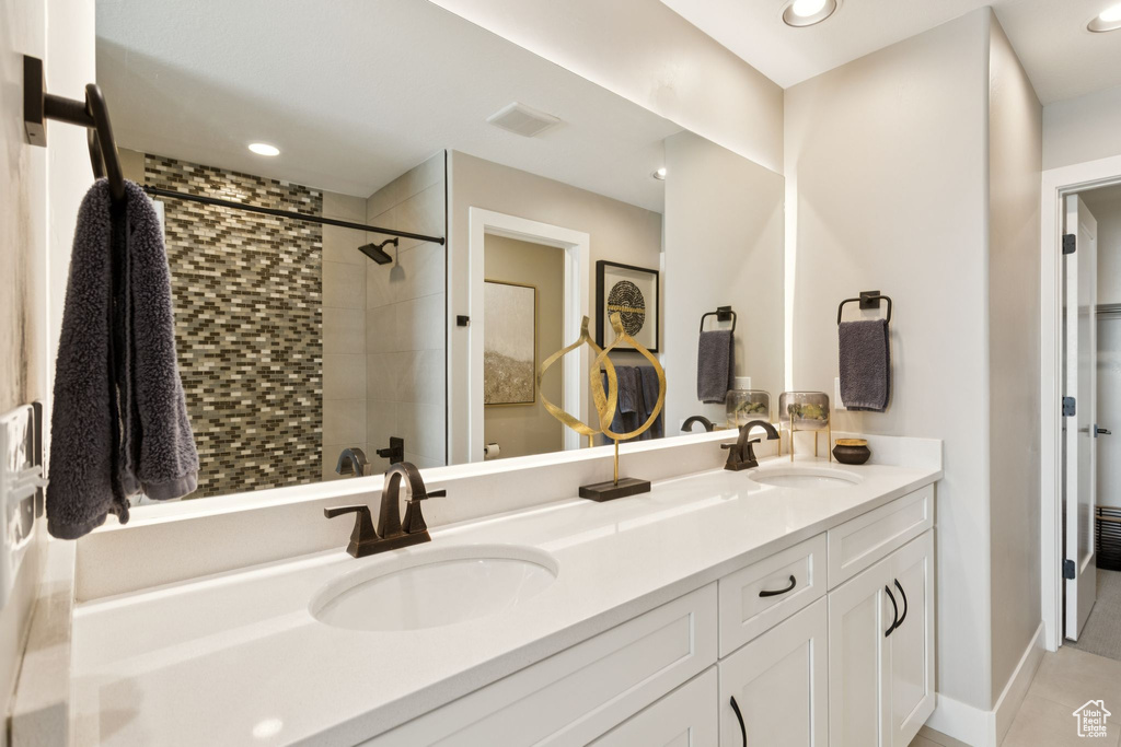 Bathroom with double vanity, a tile shower, tile patterned floors, and recessed lighting