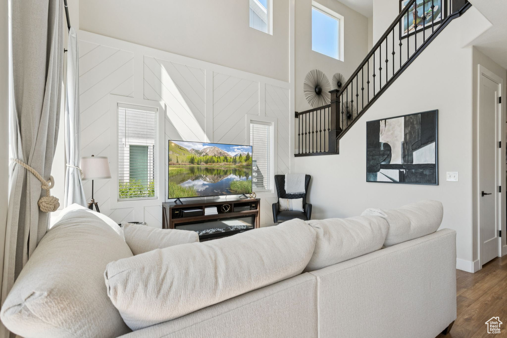 Living room featuring wood finished floors, a towering ceiling, and stairway